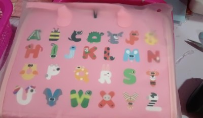 Colorful alphabet learning board for toddlers, featuring playful animal designs and a soft pink background.